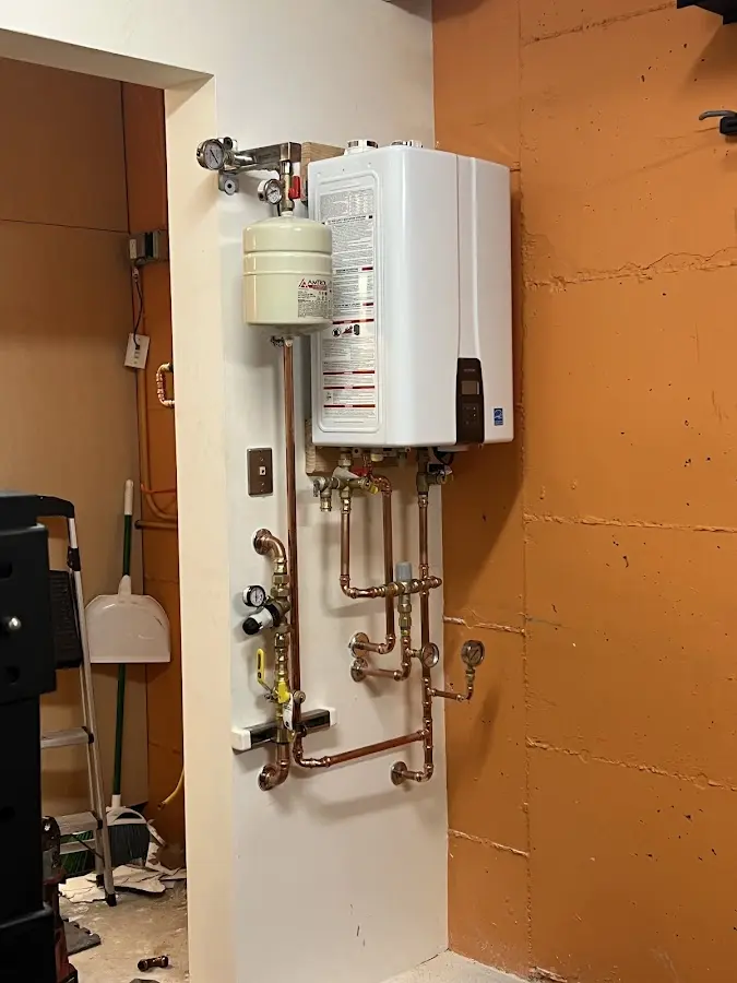 Plumbing technician inspecting water heater connections in Winchendon